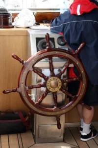 Crew member at the steering wheel of a sailing yacht at sea