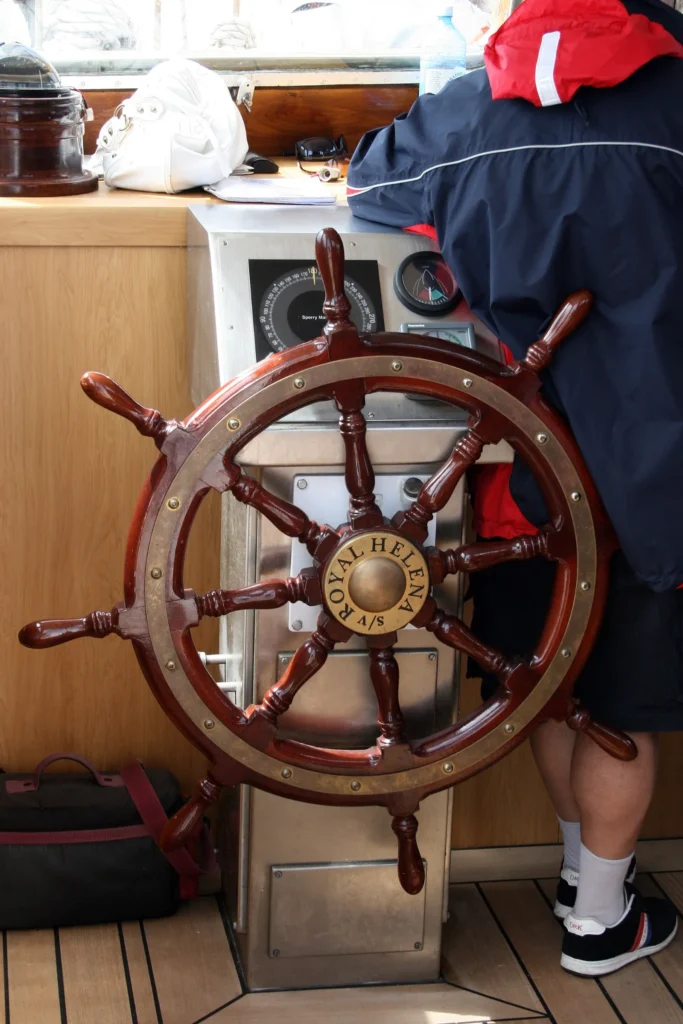 Crew member at the steering wheel of a sailing yacht at sea