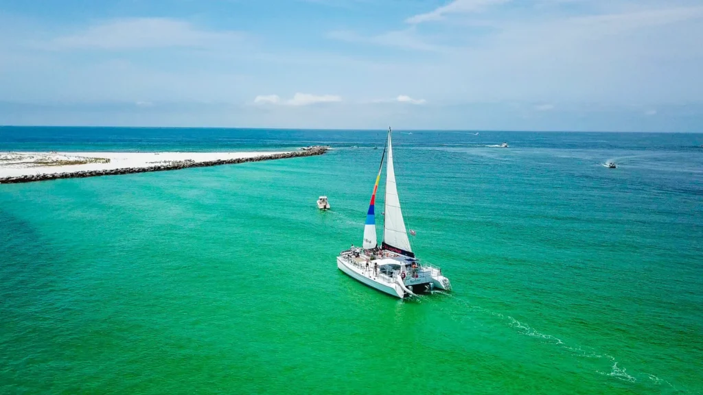 Sailing catamaran under sail on turquoise water, seen from above