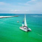 Sailing catamaran under sail on turquoise water, seen from above