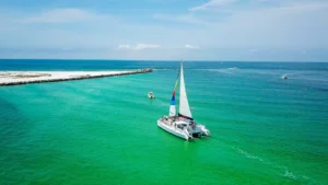 Sailing catamaran under sail on turquoise water, seen from above