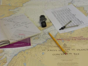 A nautical chart, logbook and navigation tools used to plan a yacht delivery