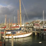 Sailing yachts moored at a marina pontoon under a dramatic sky